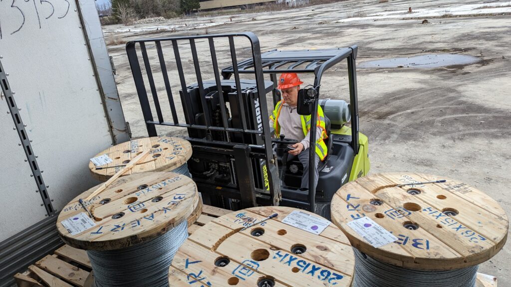 Rhoda unloads spools of strand, which is used to support fiber-optic cables, at Archtop Fiber’s storage area.