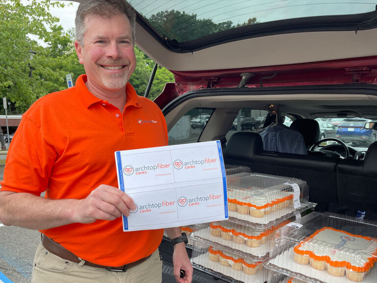 An Archtop Fiber representative poses with a car full of cupcakes for the community