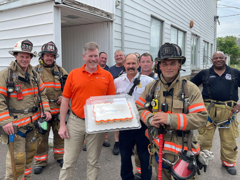 An Archtop Fiber representative delivers cupcakes and poses with members of the Kingston Fire department