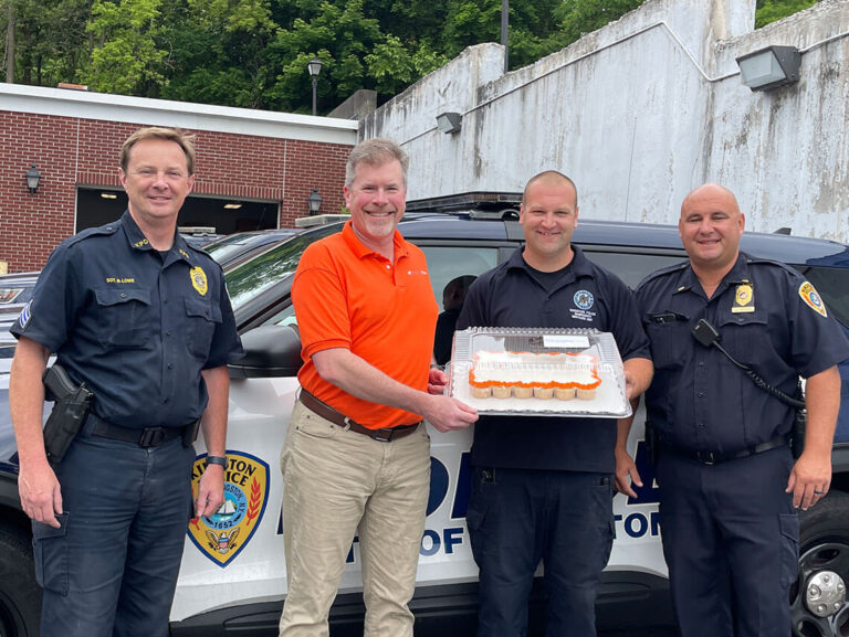 An Archtop Fiber representative delivers cupcakes and poses with members of the Kingston Police department